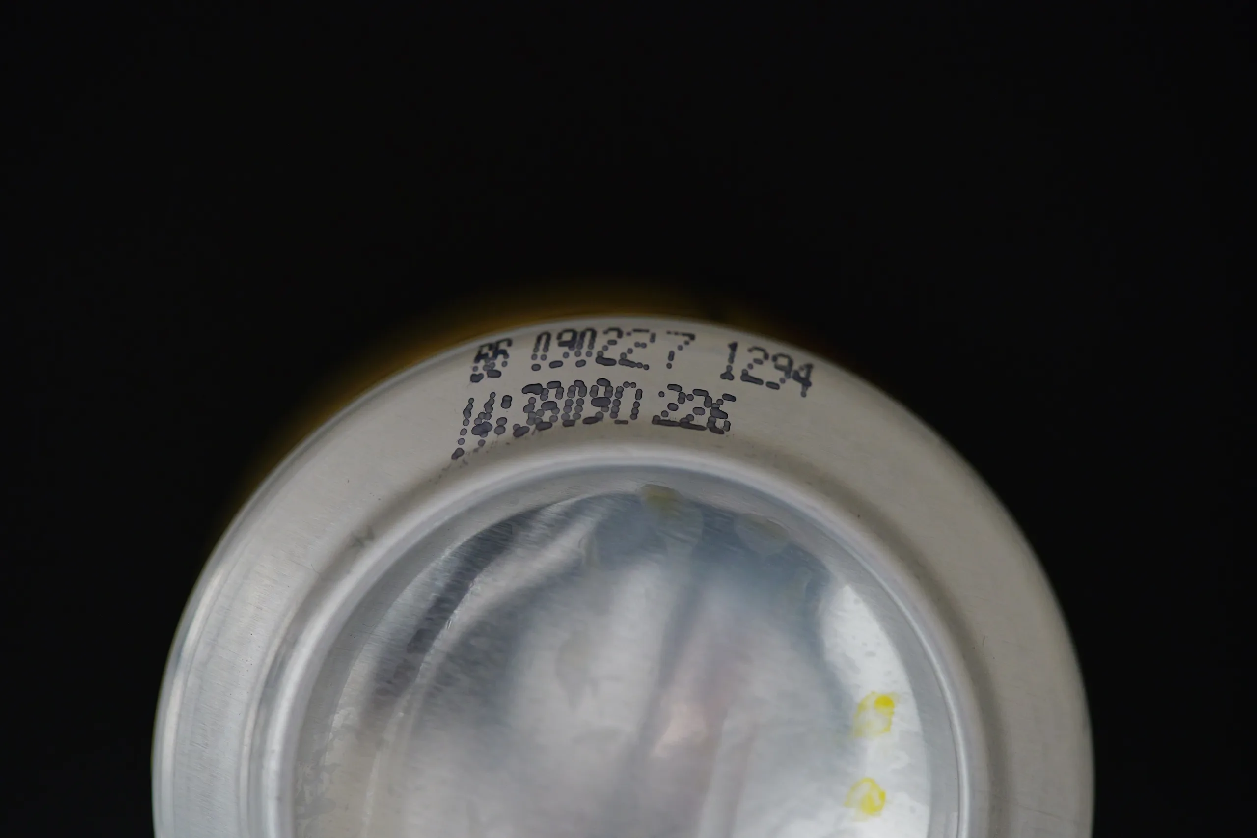 Printed date and batch codes on an aluminium can base.